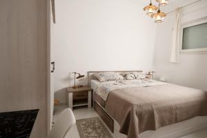 a white bedroom with a bed and a chair at Apartment Frida Rab in Banjol