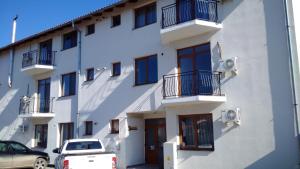 a white building with cars parked in front of it at Hotel Apart Tel Aviv in Sebeş