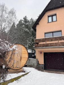 um barril de madeira sentado fora de uma casa na neve em Chata s panoramatickou saunou em Chyše