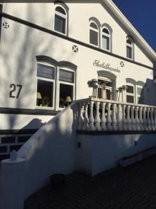 a white house with a white railing and windows at Skovbakkegaardens Bed & Bath in Aalborg