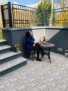 una mujer sentada en una mesa en un patio en Skovbakkegaardens Bed & Bath, en Aalborg