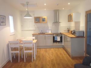 a kitchen with white cabinets and a table and chairs at The Gallery Two Bedroom Apartment in Oakham