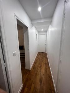 un pasillo vacío con paredes blancas y suelo de madera en New Entiry apartment-Private rooms in Paris en París