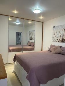 1 dormitorio con 1 cama grande y espejo grande en Apart Barra da Tijuca, en Río de Janeiro