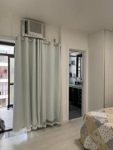 1 dormitorio con 1 cama con cortinas y calentador en Apart Barra da Tijuca, en Río de Janeiro