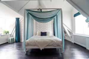 Uniek, slapen in De Graenkoper (De Rijp): 120 m2 في دي رايب: غرفة نوم مع سرير مظلة مع ستائر زرقاء