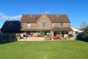 a large brick house with a large yard at Drystone Manor - Swim Hot Tub, Tennis, Gatherings in Iron Acton