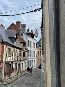 twee mensen lopen door een straat met gebouwen bij La maison St Jean in Honfleur
