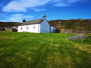 a white house in the middle of a green field at Kirtomy Cottage, Kirtomy, near Farr Beach, Bettyhill and Thurso in Farr