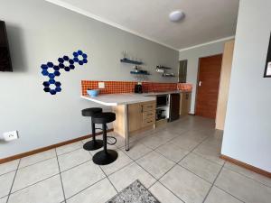 a kitchen with a counter and a table withools at 1One1@Boneyard in Jeffreys Bay