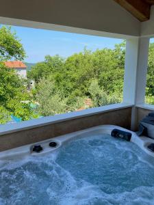 a jacuzzi tub in a room with a large window at Wellness House Oliva with heated salt water Pool, Sauna & Jakuzzi in Labin