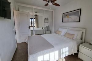 Un dormitorio con una cama blanca con ventilador de techo. en Apartamento Brisas del Mar, en San Miguel de Abona 8 fotos más