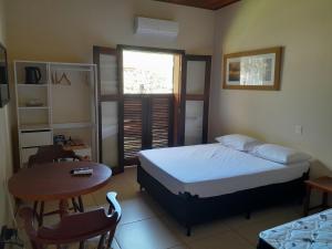 a bedroom with a bed and a table and a desk at Residencial Seestern - Suítes in Cananéia