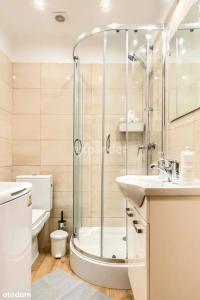 La salle de bains est pourvue d'une douche, d'un lavabo et de toilettes. dans l'établissement LUKSUSOWY Gaj Apartament, à Wrocław