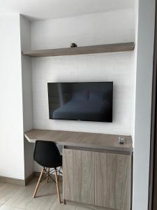a desk with a television and a chair in a room at Apartamento de lujo Manizales in Manizales