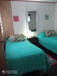 una camera d'albergo con due letti e una televisione di HOSTAL FAMILIAR a Chillán