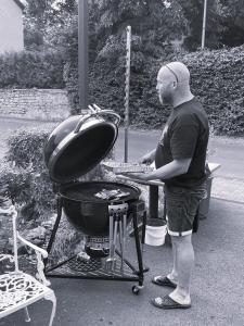 Um homem está a cozinhar comida numa grelha. em Pension zur Quelle em Deudesfeld