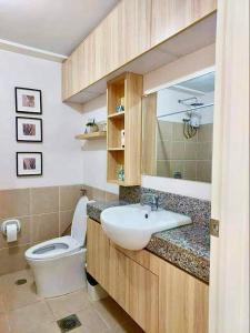 La salle de bains est pourvue d'un lavabo blanc et de toilettes. dans l'établissement Celandine by DMCI - JM staycation, à Manille