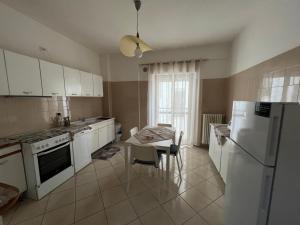 una cucina con elettrodomestici bianchi e tavolo con sedie di L'AQUILA 99 HOME a L'Aquila