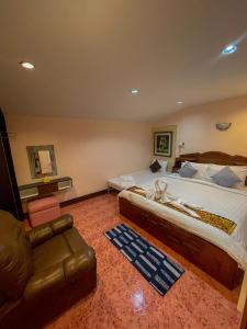 een grote slaapkamer met een groot bed en een bank bij JB Grand Resort in Nakhon Si Thammarat
