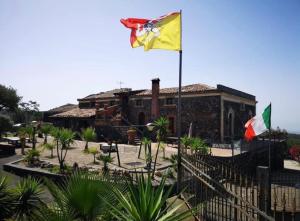Zwei Flaggen fliegen vor einem Gebäude in der Unterkunft Villa Casina dell'Etna in Ragalna