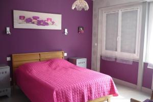 een paarse slaapkamer met een bed met een roze deken bij Calme et sérénité au gîte des hortensias in Vaux-en Couhé