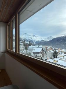 a window with a view of a snowy mountain at New! Cozy, central apartment with a stunning view in St. Moritz