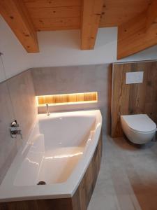 uma casa de banho com uma banheira branca e um WC. em Appartamento l’ Aier - Arabba - Dolomiti em Livinallongo del Col di Lana
