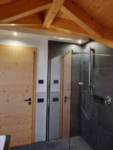 La salle de bains est pourvue d'une douche et d'une porte en bois. dans l'établissement Appartamento l’ Aier - Arabba - Dolomiti, à Livinallongo del Col di Lana