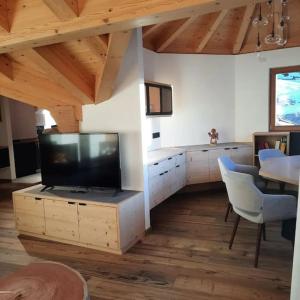 uma sala de estar com uma televisão de ecrã plano e uma mesa em Appartamento l’ Aier - Arabba - Dolomiti em Livinallongo del Col di Lana