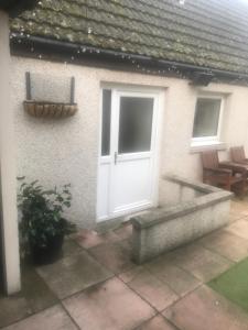 a house with a white door and a patio at Lovely 1-Bed Cottage in Hopeman in Elgin