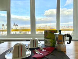 雅西的住宿－Inima Iasului - Central View Apartment，桌子上带两个杯子和盘子的桌子,有窗