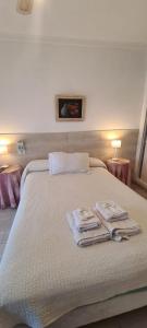 a white bed with two towels and two lamps at Hotel Soleares in Mar del Plata