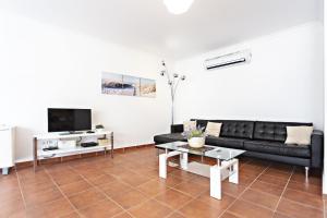 sala de estar con sofá negro y TV en Lavender Apartment en Santa Luzia