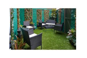 a patio with chairs and tables and a green wall at Home @ 2 Tancred Road in Liverpool