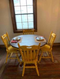 a wooden dining room table with four chairs and a window at Hanna’s Cottage-Downtown Hermann in Hermann