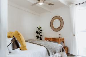 a white bedroom with a bed and a mirror at Sea Siren in Paternoster