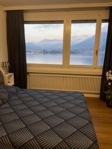 Dormitorio con ventana grande con vistas al agua en Alloggio con favolosa vista lago Lugano Paradiso en Paradiso
