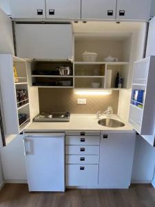 a small kitchen with white cabinets and a sink at Alloggio con favolosa vista lago Lugano Paradiso in Paradiso