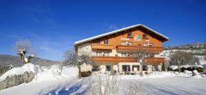 un grand bâtiment avec de la neige devant lui dans l'établissement Logis Hotel Les Playes, à Villard-de-Lans