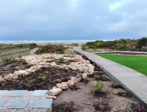 a garden with a walkway next to the beach at Soli Deo Gloria, Pearl Studio - Solar in Paternoster