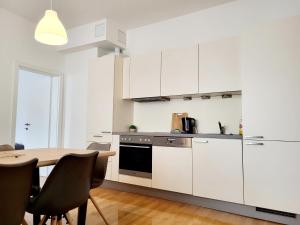 a kitchen with white cabinets and a table with chairs at Floridsdorfer Apartment - Free Highspeed-Internet in Vienna +28 photos