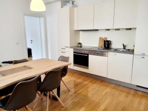 a kitchen with white cabinets and a wooden table and chairs at Floridsdorfer Apartment - Free Highspeed-Internet in Vienna
