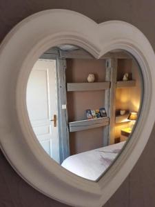 een kamer met een hartvormige spiegel en een bed bij O P'tit Bawala in Beblenheim