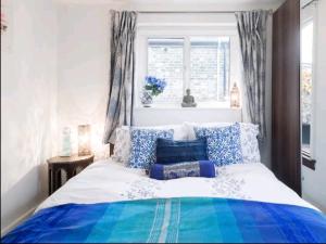a bed with blue and white pillows and a window at Stylish room with private bath & terrace in super central Clapham Junction minutes from Victoria, Waterloo in London