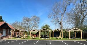 um grupo de abrigos de piquenique com mesas e cadeiras num parque de estacionamento em The Black Horse Inn em Gainsborough