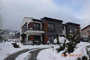 uma casa está coberta de neve com uma entrada em Apartament Spokojny em Wisla
