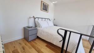 a white bedroom with a bed and a night stand at The Studio Room at Wester Den in Arbroath