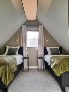 sypialnia na poddaszu z 2 łóżkami i oknem w obiekcie De Groene Bever w mieście Lo-Reninge