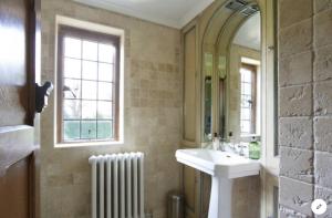 a bathroom with a sink and a mirror and a radiator at B&B Harlington Manor in Harlington
